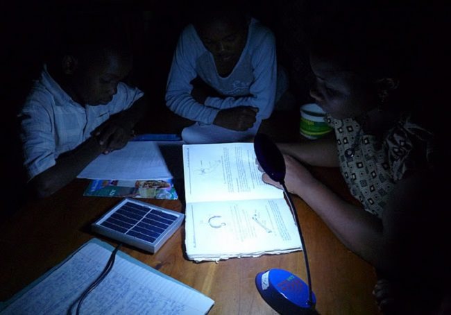 Schoolchildren studying by the light of a solar lamp in Tanzania.
