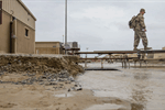 A soldier walks across a makeshift bridge of picnic tables to avoid flood waters at Camp Arifjan, Kuwait, in November 2018. A soldier walks across a makeshift bridge of picnic tables to avoid flood waters at Camp Arifjan, Kuwait, in November 2018.