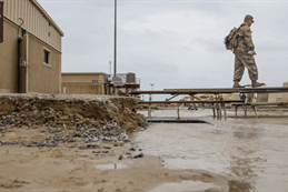 A soldier walks across a makeshift bridge of picnic tables to avoid flood waters at Camp Arifjan, Kuwait, in November 2018. A soldier walks across a makeshift bridge of picnic tables to avoid flood waters at Camp Arifjan, Kuwait, in November 2018.